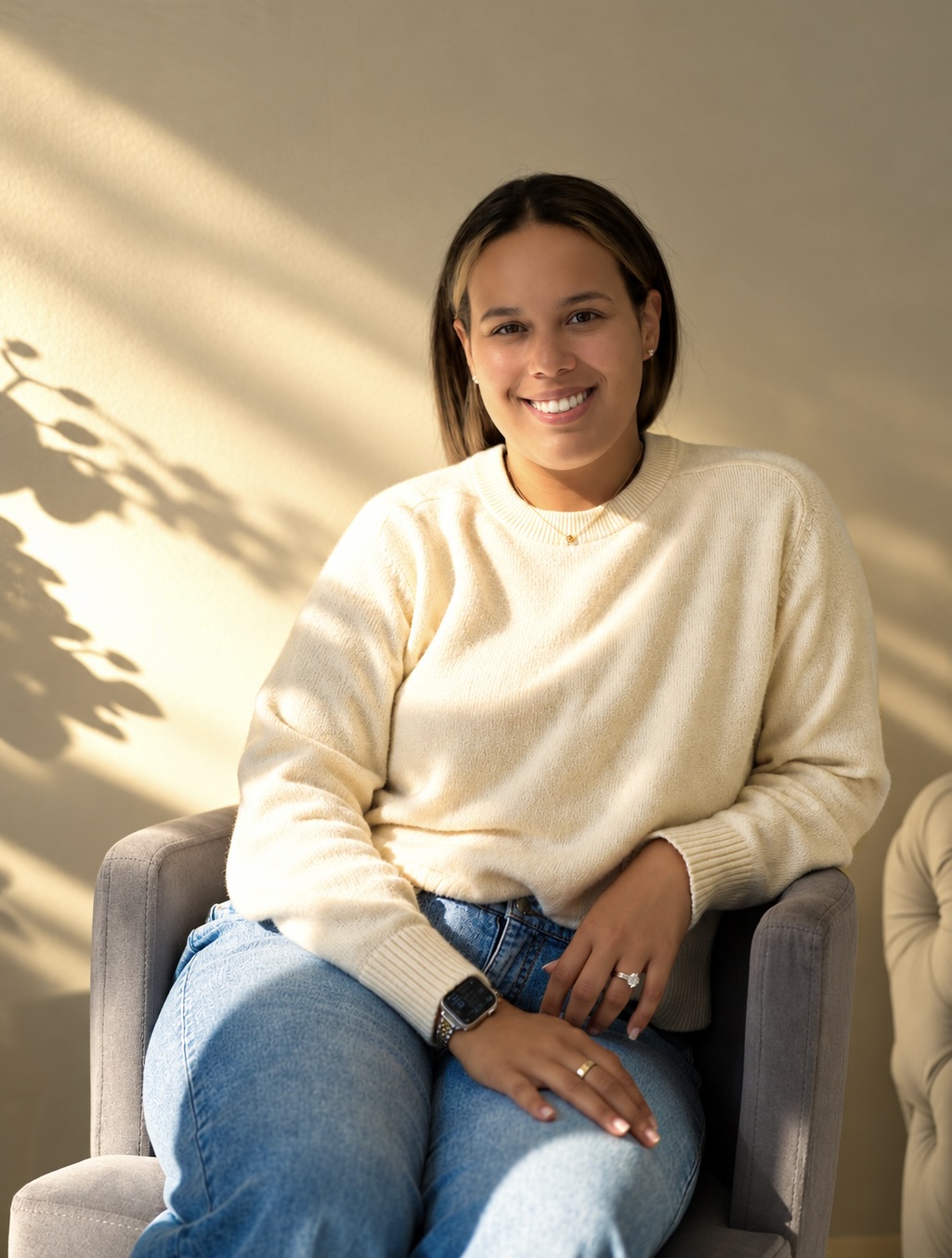 Karen smiling in a cream sweater, seated in warm sunlight